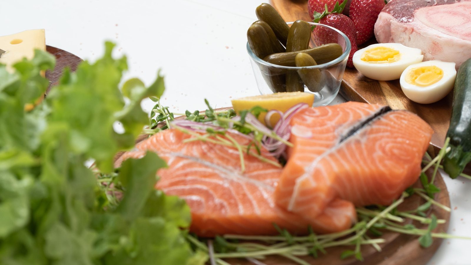 Fresh salmon, greens, eggs and vegetables laid out on a board