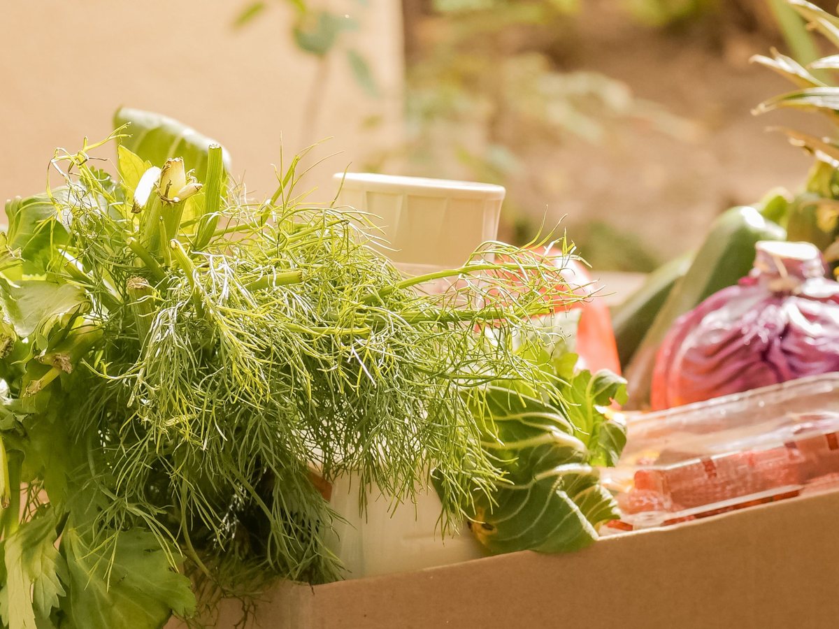 A box filled with fresh greens, cabbage and pineapple