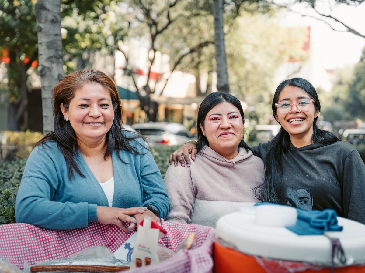 Three friends sharing a table at an outdoor gathering